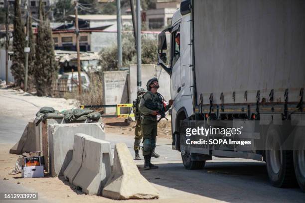 Israeli soldiers prevent a vehicle from entering after they closed the road in the town of Hawara, during intensive searches for the attacker of two...