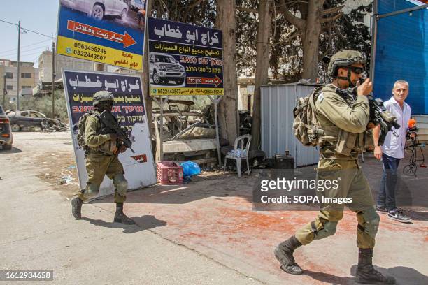 Israeli soldiers inspect the car wash where the shooting took place, where two Israeli settlers were killed, during intensive searches for the...