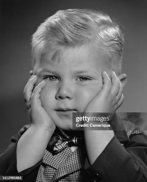 Young boy puts his fingers in his ears to avoid hearing something.