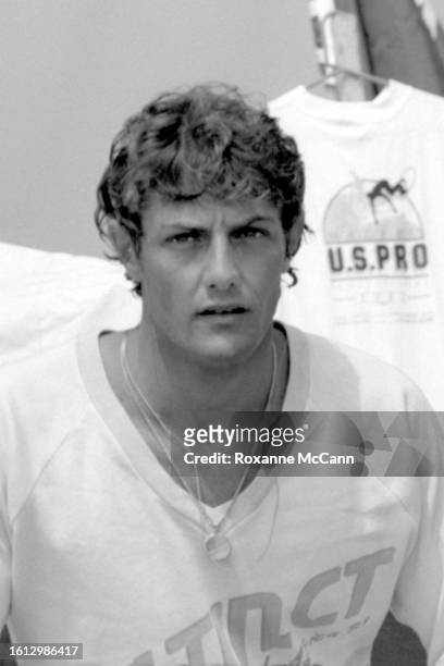 South African surfer Shaun Tomson stands in front of a U.S. Pro t-shirt wearing a shirt from his clothing brand Instinct and a medallion necklace at...
