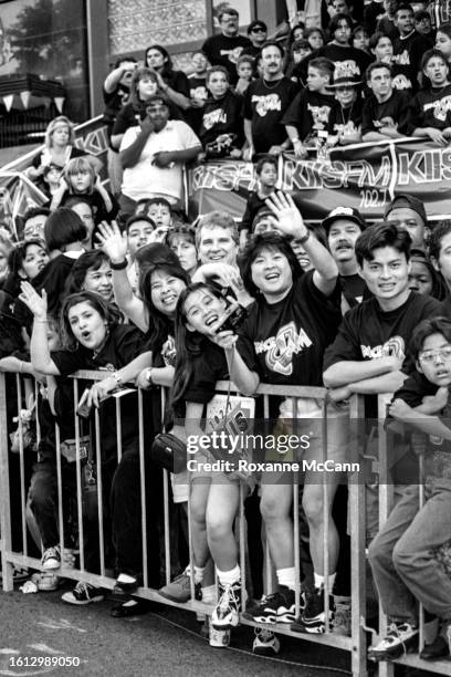 Fans wearing Space Jam t-shirts are held behind barricades on bleachers with KIIS FM banners screaming and waving at guests arriving for the premiere...