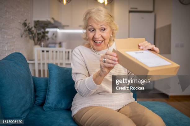 senior woman is holding cardboard box - elderly receiving paperwork stock pictures, royalty-free photos & images