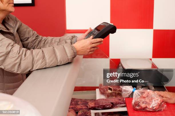 customer using credit card terminal to paid meat - cnglbus264expertisereal peopleservice stock pictures, royalty-free photos & images