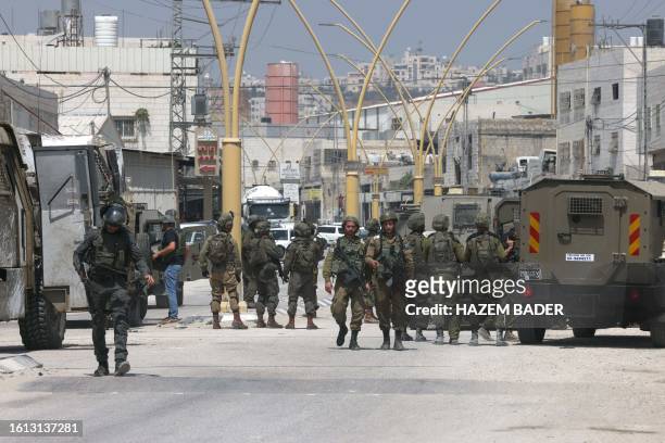 Members of Israeli security forces block a road leading to the site of a reported attack south of Hebron in the occupied West Bank, on August 21,...