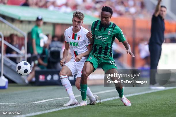 Arne Engels of FC Augsburg and Nathan Ngoumou of Borussia Moenchengladbach battle for the ball during the Bundesliga match between FC Augsburg and...