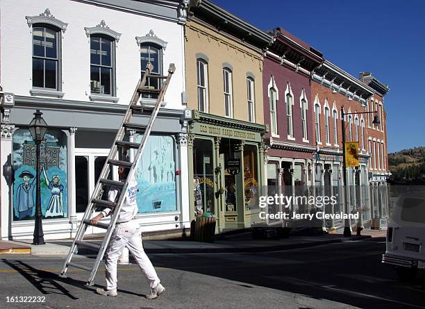 October 15, 2003 - Dan Buxman of Silva Paints in Denver carries a ladder across Lawrence Street to a painting job at the old Masonic Hall in Central...