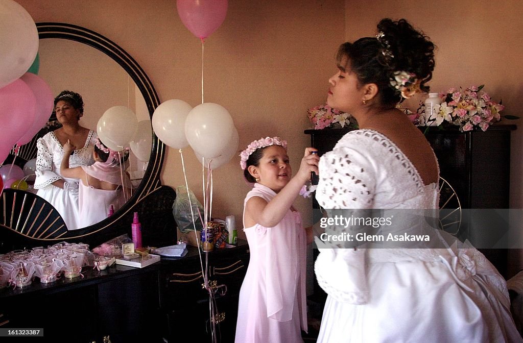 Patricia Chavez, 10, of Denver, sprays perfume on her cousin, Gabriela Garcia, as the two get ready for Garcia's quinceanera--or 15th birthday celebration, at her family's hometown of El Tepetate, Mexico on Valentine's Day. DENVER POST PHOTO BY GLENN ASAK