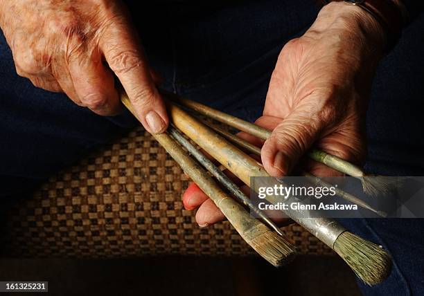 Year-old Wayne K. Patterson, former prison warden, holds a few of the brushes he uses to paint with in his garage studio at his home in Canon City....