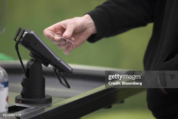 Customer taps a credit card at a self-service checkout kiosk at a Woolworths Group Ltd. Grocery store in Sydney, Aug. 21, 2023. Woolworths is...