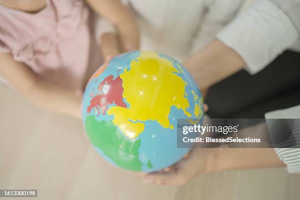 elementary and preschool girls learning world map with model globe with teacher in montessori education school - globes showing earth with all continents stock pictures, royalty-free photos & images