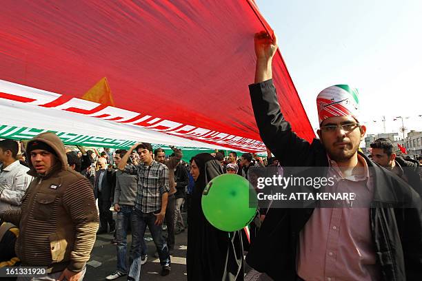 Iranians carry their national flag during a rally in Tehran's Azadi Square to mark the 34th anniversary of the Islamic revolution on February 10,...