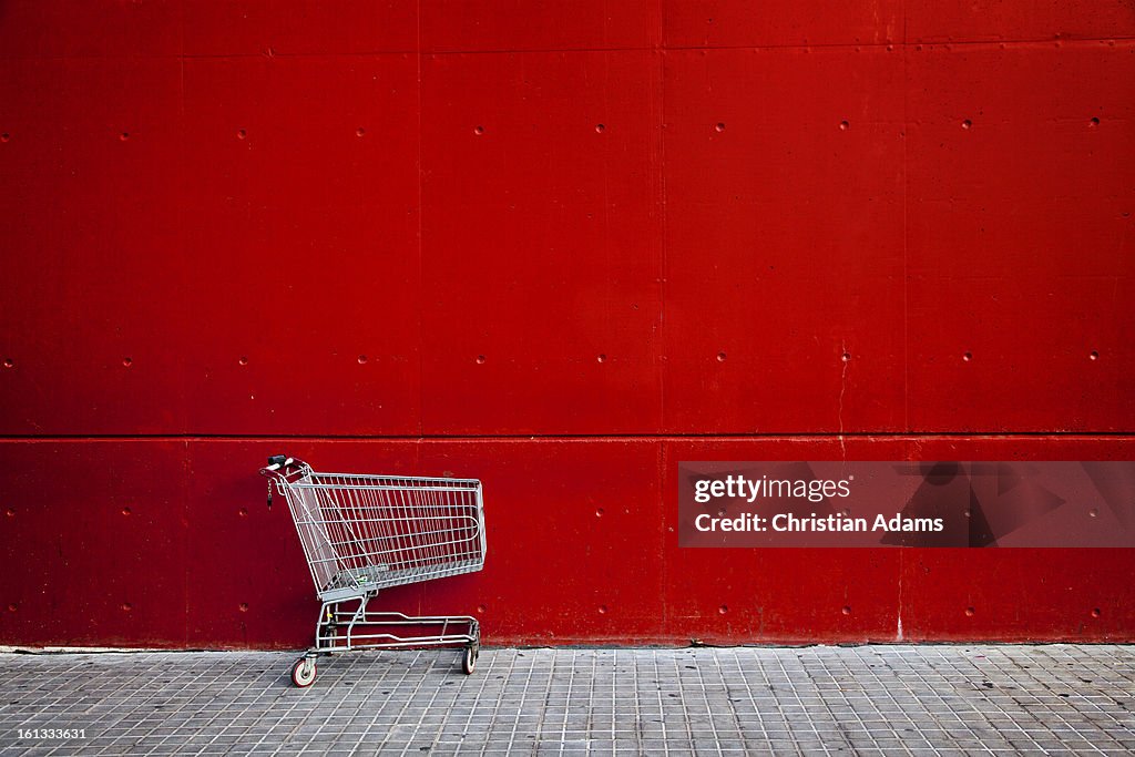 Shopping cart in front of a red wall