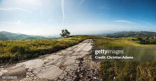 broken tar road - beaten up stockfoto's en -beelden