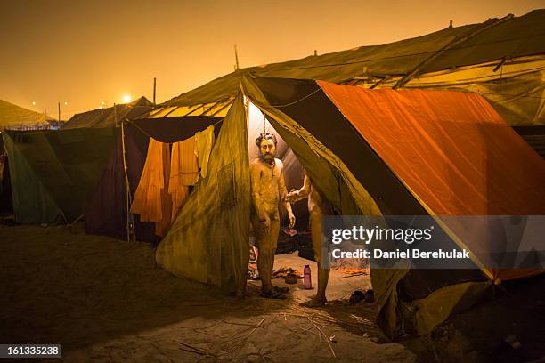 Naga Sadhus, naked Hindu holy men, look out from their tent as they prepare themselves early morning prior to participating in a procession to bathe...