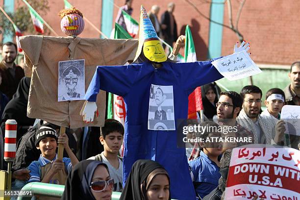 Iranians hold up two effigies, one with the image of US President Barack Obama pinned to it and the other with an image the late and deposed Shah of...