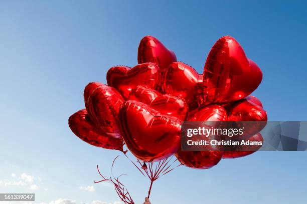 a bunch of red heart-shaped balloons - herz luftballons stock-fotos und bilder