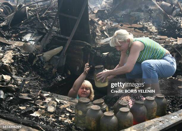 Russian women remove food conserves from the underground basement of their burnt out home 15km from Moscow in Ostafyevo on August 2, 2010. Russian...