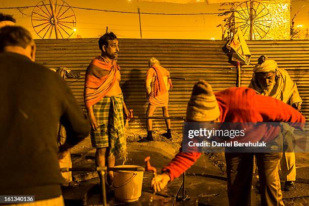 Sadhu, Hindu holy man, and other devotees prepare themselves early morning before making their way to bathe on the banks of Sangam, the confluence of...