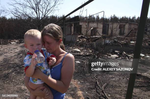 Russian woman holding a baby cries near the remains of her burnt out home in Voronezh on August 1, 2010. Firefighters fought an uphill battle against...