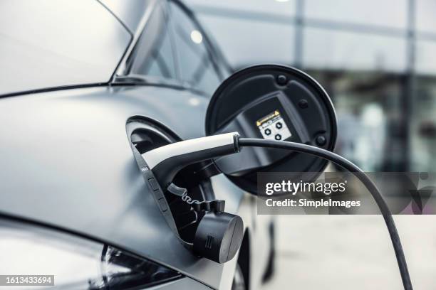 electric plug cable connects from electric charging station to ev car being charged. - power supply stock pictures, royalty-free photos & images