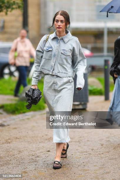 Guest wears a black and white polka dots print pattern umbrella, a pale blue denim jacket, a matching pale blue faded denim long skirt, a dark brown...