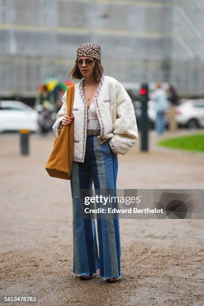 Guest wears a beige and brown leopard print pattern silk scarf as a headband, a white latte corset top, a white embossed tweed with red and blue...