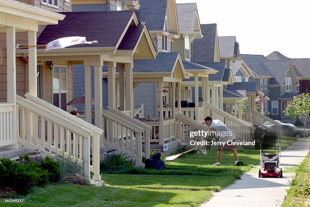 Isaac Hernandez, homeowner in Commerce City's Belle Creek Community, rakes up grass in his front yard after mowing Tuesday afternoon, 5/20/03. (The Denver Post / Jerry Cleveland)