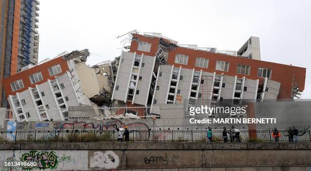 Passers-by observe the remains of a destroyed building in Concepcion on February 28 a day after a huge 8.8-magnitude earthquake rocked Chile early...