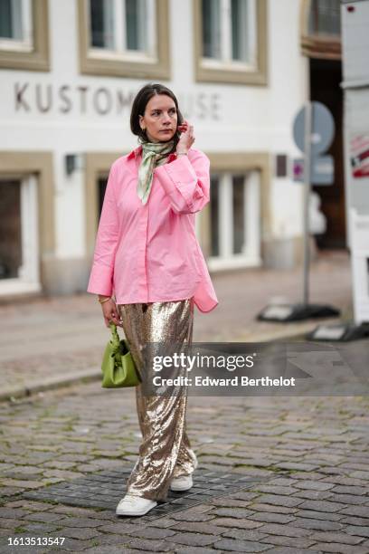 Guest wears gold earrings, a pale green and beige checkered print pattern silk scarf, a pale pink shirt, gold embroidered sequined wide legs pants, a...