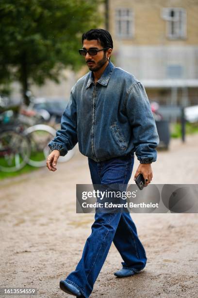 Guest wears black sunglasses, a blue denim zipper bomber coat, navy blue denim large pants, blue denim pointed heels shoes , outside OperaSport,...