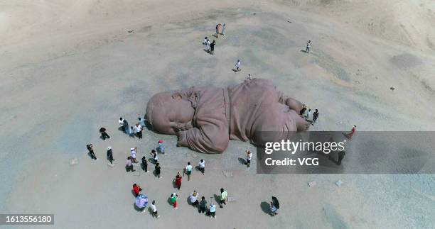 People visit the sculpture 'Son of the Earth', a huge 3D baby statue sleeping on the vast Gobi Desert, on August 13, 2023 in Jiuquan, Gansu Province...