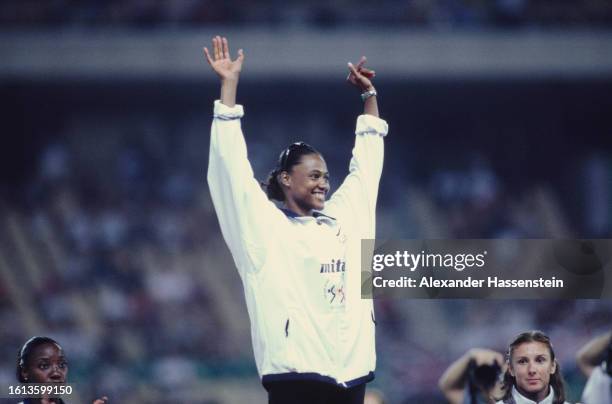 American athlete Marion Jones, her arms raised in celebration, on the winners' podium during the medal ceremony following the women's 100 metres...