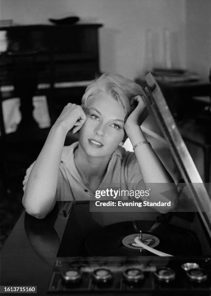 Actress Anne Aubrey listens to music while leaning on a record player, October 15th, 1959.