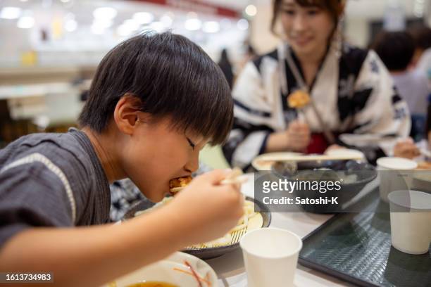 little boy eating fried chicken and udon noddle in food court - udon noodle stock pictures, royalty-free photos & images