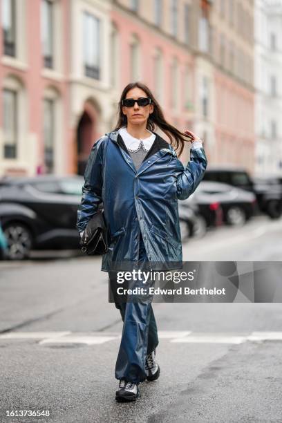 Guest wears black sunglasses, a white large collar shirt, a pale gray wool pullover, a blue shiny with gray reflect oversized coat, matching pants, a...