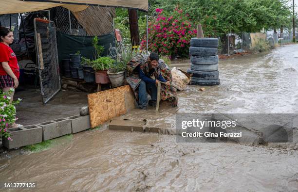 Sergio Lopez of Thermal drags a large wooden plank to the front of his friend's mobile home to help divert the flood water running on Avenue 70...