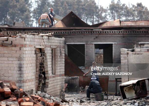 Russian men clean up debris from the charred remains of a burnt out home in Voronezh on August 5, 2010. Russia struggled to contain the worst...