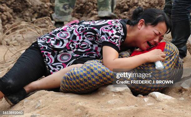 Woman cries over the dead body of her child, wrapped in blankets amid the rubble of landslide devastation in Zhouqu on August 11, 2010 in northwest...