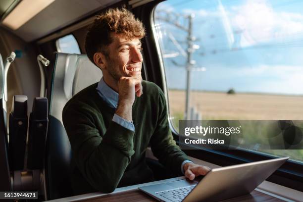 ein mann, der während einer zugfahrt einen laptop benutzt - pendler bahn stock-fotos und bilder