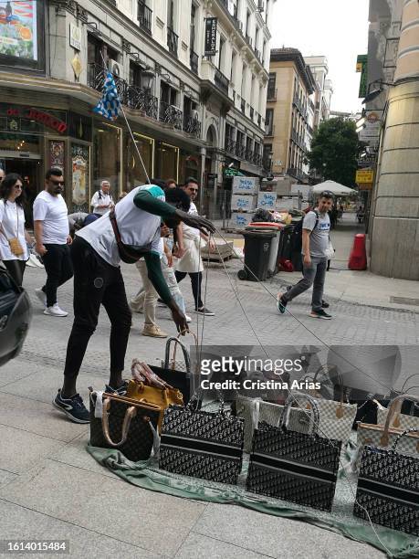 Immigrants selling fake luxury brand bags and other products, in a street in the center of Madrid May 2023 in Madrid, Spain.