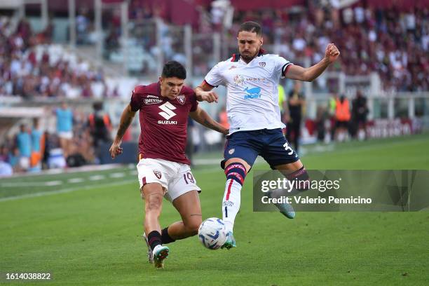 Raoul Bellanova of Torino FC is challenged by Paulo Azzi of Cagliari Calcio during the Serie A TIM match between Torino FC and Cagliari Calcio at...