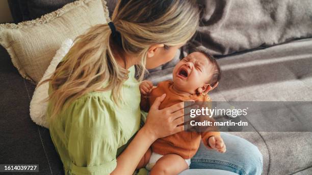young mother tries to calm her screaming newborn baby - crying baby stock pictures, royalty-free photos & images