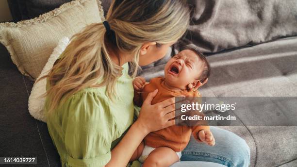 young mother tries to calm her screaming newborn baby - baby two baby stock pictures, royalty-free photos & images