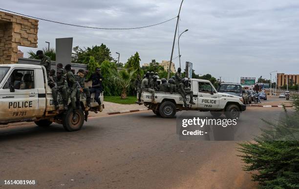 Police officer ride on the back of a pick-up truck as they patrol in Niamey on August 21, 2023.