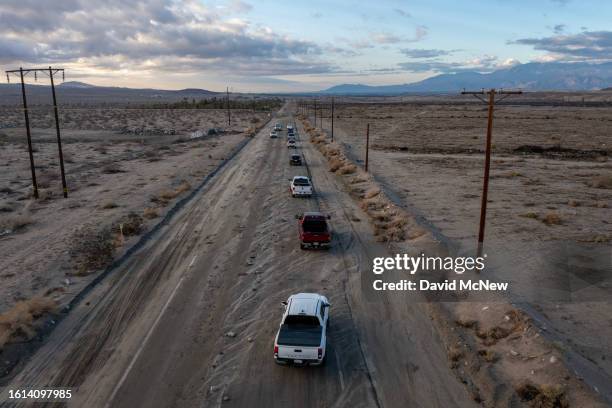 In an aerial view, a line of vehicles slowly drive down a rock-covered road that was hit by a flash flood in the aftermath of Tropical Storm Hilary...