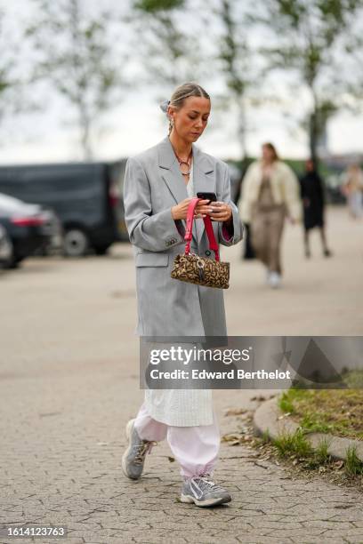 Guest wears a pale gray long blazer jacket, a white striped print pattern long jacket, pale pink puffy pants, gray sneakers, a beige with embroidered...