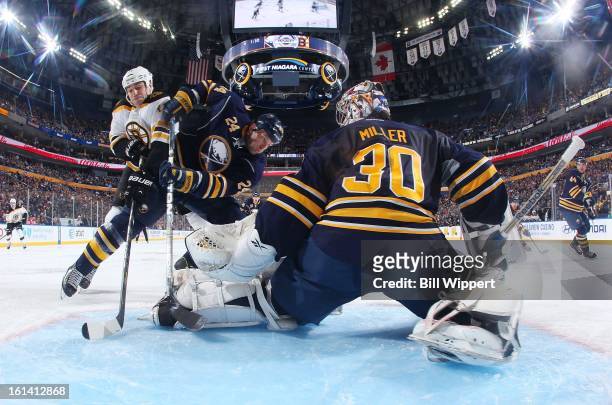 Ryan Miller of the Buffalo Sabres makes a save in front of teammate Robyn Regehr and Milan Lucic of the Boston Bruins on February 10, 2013 at the...