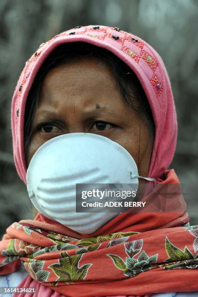 Woman covers her mouth with a mask as she examines her house covered with ash following the October 27 Merapi volcano eruption, in Kaliadem, Sleman...