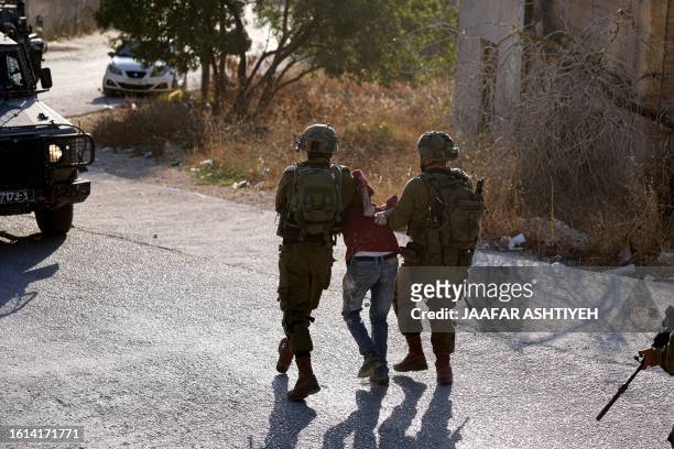 Israeli soldiers arrest a Palestinian man during a search operation in Baita village in the occupied West Bank, on August 21, 2023.