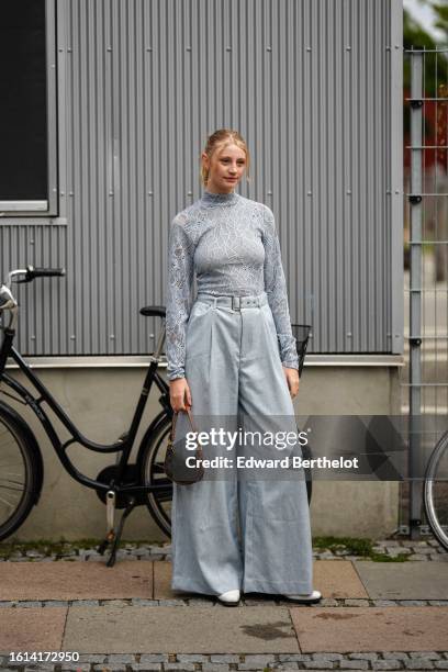 Guest wears a pale blue cut-out lace print pattern turtleneck / long sleeves top, pale gray wide legs pants, a brown logo print pattern in coated...